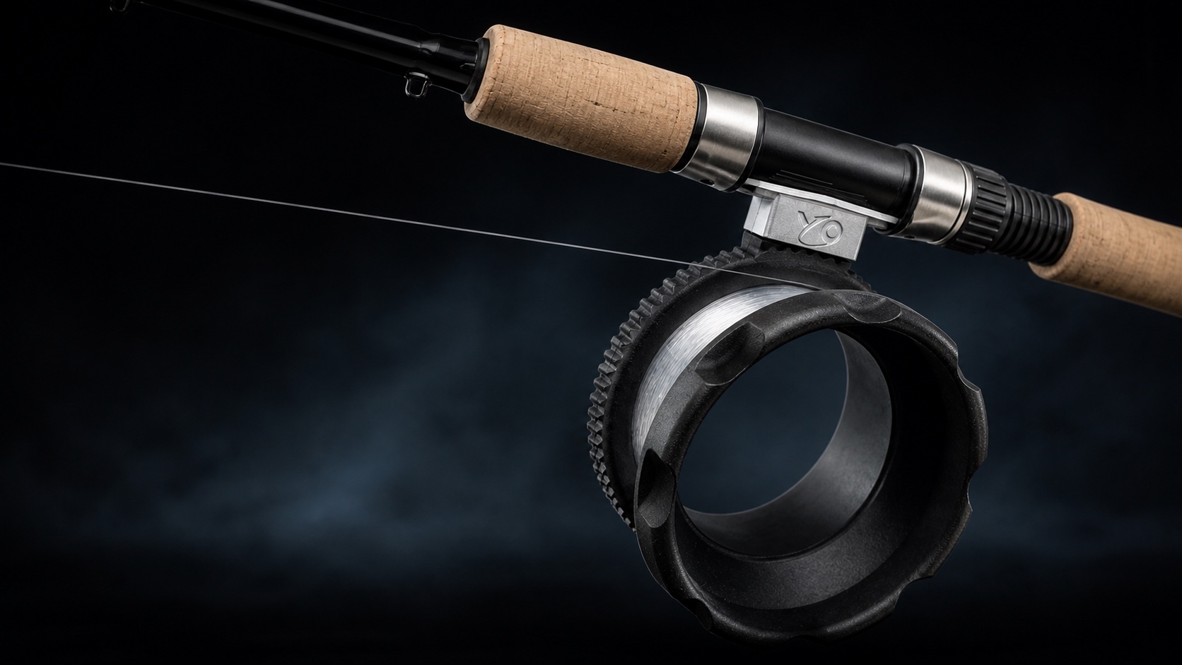 YO Reel mounted on a cork-handled rod against a dark graphite studio backdrop